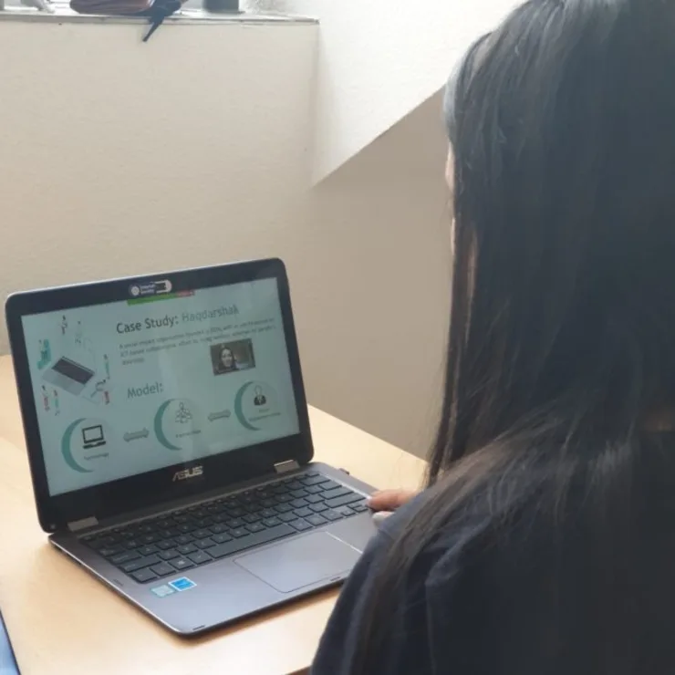 A student presenting her work in front of a computer screen
