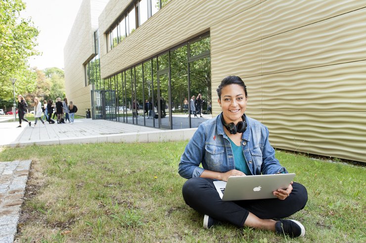 Student sitting on a field holding a computer