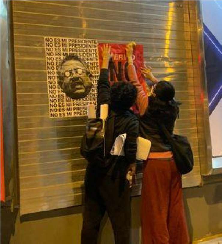 Two young Peruvians hang a poster with the image of Manuel Merino and the phrase “Not my President” on the background on the streets of Miraflores, Lima. Credits: Grecia Pillaca, personal archive